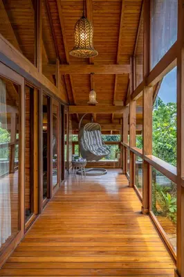 a wooden hallway of a house with a chair at amã Stays and Trails The Malabar Villa Hibiscus, Kozhikode in Puthuppādi