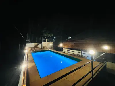 a swimming pool at night with lights at Paroommel Haven Wayanad in Kenichira