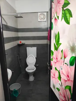 a bathroom with a toilet with pink flowers on the wall at Sajeev Home Stay in Cherai Beach