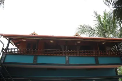 a building with a balcony with palm trees in the background at Sajeev Home Stay in Cherai Beach