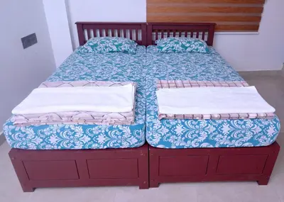 a bed with a wooden frame with two pillows on it at Chittinappilly Cottage in Angamali