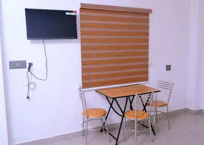 a table and chairs in a room with a tv at Chittinappilly Cottage in Angamali