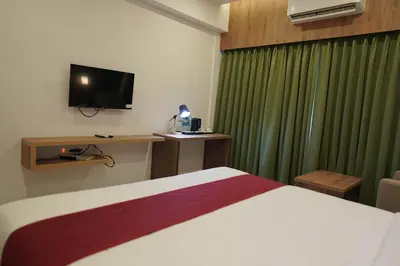 a hotel room with a bed and a television at HOTEL VKJ INN Aluva in Alwaye