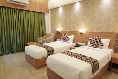 two beds in a hotel room with green curtains at HOTEL VKJ INN Aluva in Alwaye