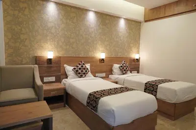 a hotel room with two beds and a chair at HOTEL VKJ INN Aluva in Alwaye
