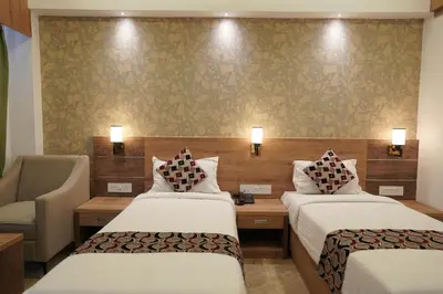 a hotel room with two beds and a chair at HOTEL VKJ INN Aluva in Alwaye