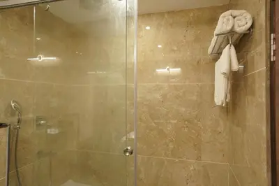 a shower stall with a glass door in a bathroom at HOTEL VKJ INN Aluva in Alwaye