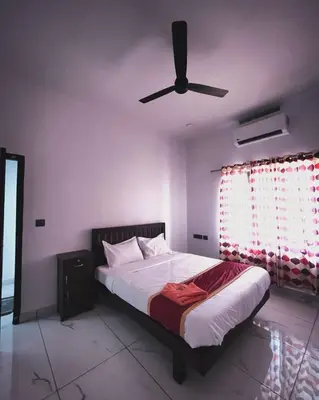 a bedroom with a bed with a ceiling fan at MATHER RAJAGIRI FURNISHED APARTMENTS in Alwaye