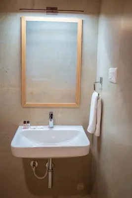 a white sink in a bathroom with a mirror at HOTEL ACHYUT in Tiruppūr
