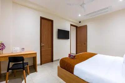 a bedroom with a bed and a desk and a chair at HOTEL ACHYUT in Tiruppūr