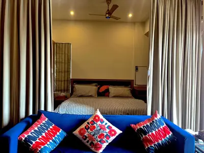 a bedroom with a bed and a blue couch with pillows at Green Horizon, Luxury & Nature at Kothamangalam in Kotamangalam
