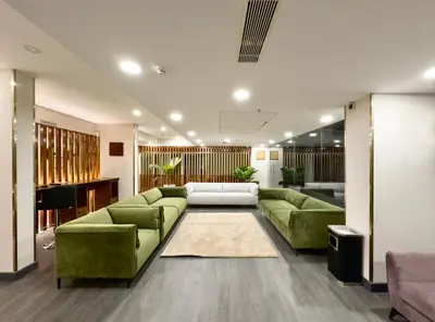 a living room with green couches and a piano at The Habitat Suites-Walkable distance to Guruvayoor temple in Guruvāyūr
