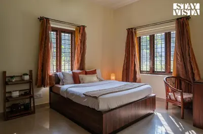 a bedroom with a bed and two windows at StayVista at Nature Nook with Pvt Pool & Terrace Access in Trichūr