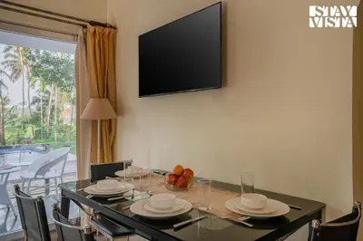 a dining room with a table with a television on the wall at StayVista at Nature Nook with Pvt Pool & Terrace Access in Trichūr