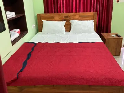 a bedroom with a bed with a red blanket at MO’s Agro in Pāppinisseri