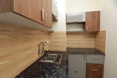 a kitchen with wooden cabinets and a sink at VVP serviceapartments cochin Airport in Nedumbassery