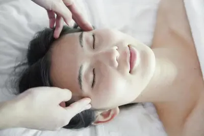 a woman laying on a bed getting her face massage at Kaira Regency in Olakara