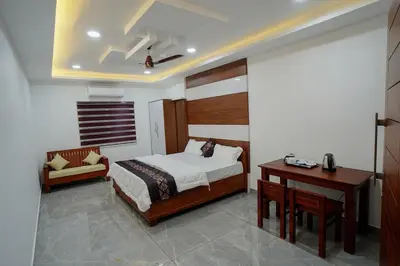 a bedroom with a bed and a table and a desk at UNIVERSAL RESIDENCY in Perumbavoor