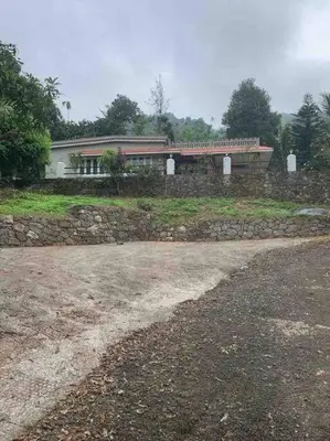 a house with a stone wall in front of it at Maskan Home Stay in Kakkadampoyil
