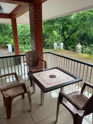 a patio with two chairs and a table on a porch at Maskan Home Stay in Kakkadampoyil