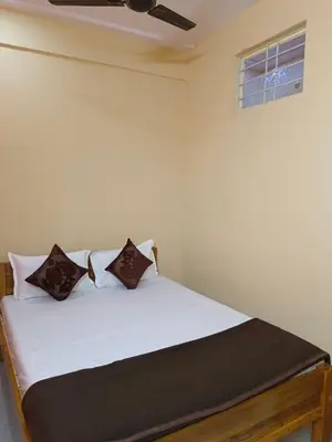 a bedroom with a bed with white sheets and a window at Royal Comforts in Mysore