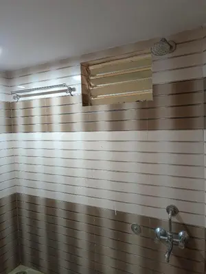 a bathroom with a brown and white tiled wall at Royal Comforts in Mysore