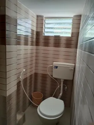 a small bathroom with a toilet and a window at Royal Comforts in Mysore