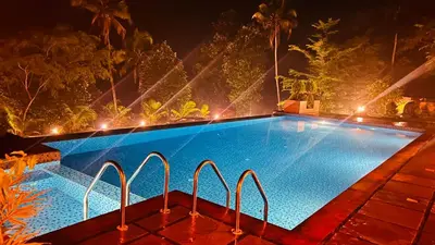 a swimming pool at night with lights at Coconut Valley in Neriyamangalam