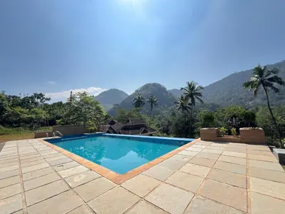 a swimming pool with mountains in the background at Coconut Valley in Neriyamangalam