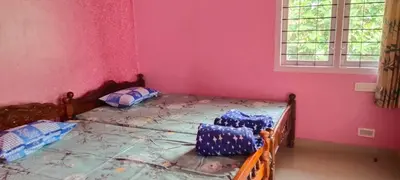 a bedroom with two beds and a pink wall at jacaranda resorts in Kanthalloor