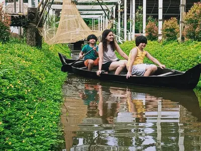 a group of people sitting on a boat in the water at Village of Blossom in Ernakulam