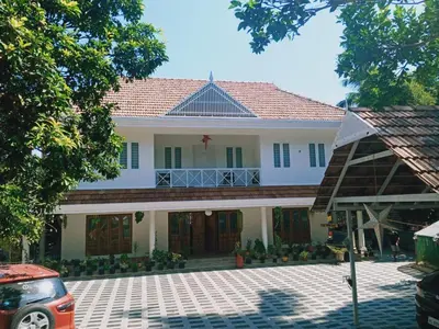 a large white house with a balcony on top of it at Village of Blossom in Ernakulam