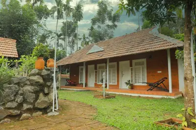 a small house with a stone wall in front of it at Village of Blossom in Ernakulam
