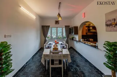 a dining room with a table and a kitchen at EKOSTAY - Moonlight Villa in Kodaikānāl