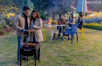 a man and woman holding a plate of food next to a grill at EKOSTAY - Moonlight Villa in Kodaikānāl
