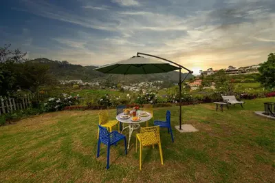 a table and chairs under an umbrella in a yard at EKOSTAY - Moonlight Villa in Kodaikānāl