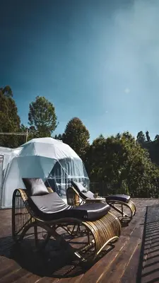 a group of chairs with an umbrella on a deck at Divercity Luxury Glamp in Kodaikānāl