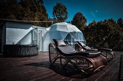 a chair on a deck with a clear umbrella at Divercity Luxury Glamp in Kodaikānāl