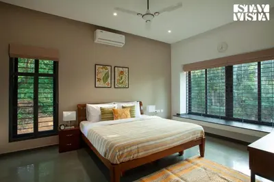 a bedroom with a bed and two large windows at StayVista at The Big Chill with Breakfast Included in Wayanad