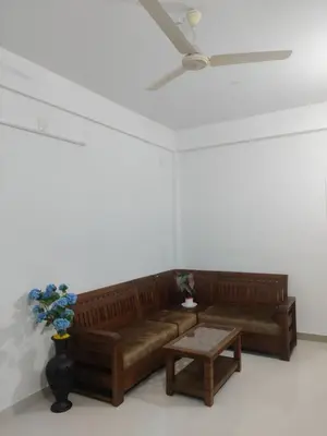 a living room with a brown couch and a table at Spacious 2BHK Near Airport in Cochin