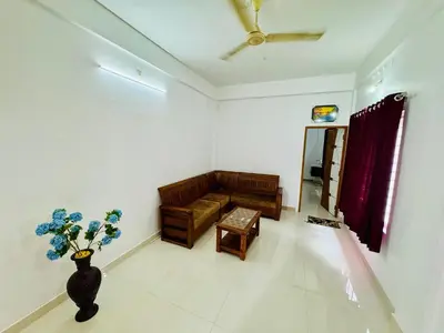 a living room with a couch and a vase of flowers at Spacious 2BHK Near Airport in Cochin