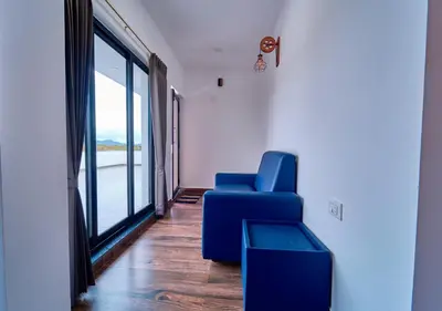 a blue chair in a room with a large window at Kodai Outdoor Valley in Kodaikānāl