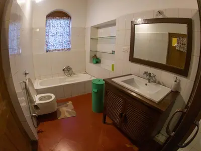 a bathroom with a sink and a tub and a toilet at LA Address Retreat - The Heritage Homestay in Ooty