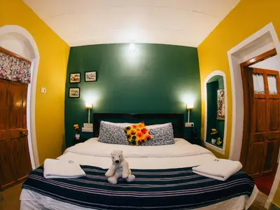 a teddy bear sitting on a bed in a bedroom at LA Address Retreat - The Heritage Homestay in Ooty