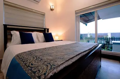 a bedroom with a large bed and a large window at Kappad Beach House by Kisah Stays in Kappad