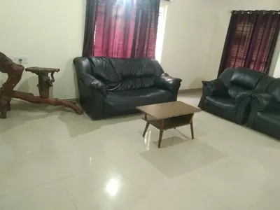 a living room with black leather chairs and a coffee table at Samz estate stay 2BHK in Madikeri
