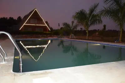 a swimming pool with a house in the background at Golden Triangle River side Cabin in Mysore