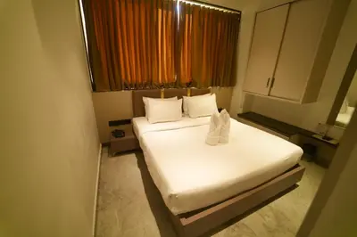 a small room with two beds and a window at Yuvraj Le: Royale in Mysore