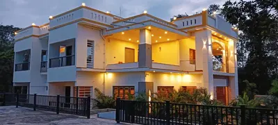 a large white house with lights on it at Coorg Le Embera in Virajpet