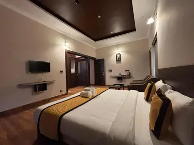 a hotel room with a large bed and a television at Coorg Le Embera in Virajpet